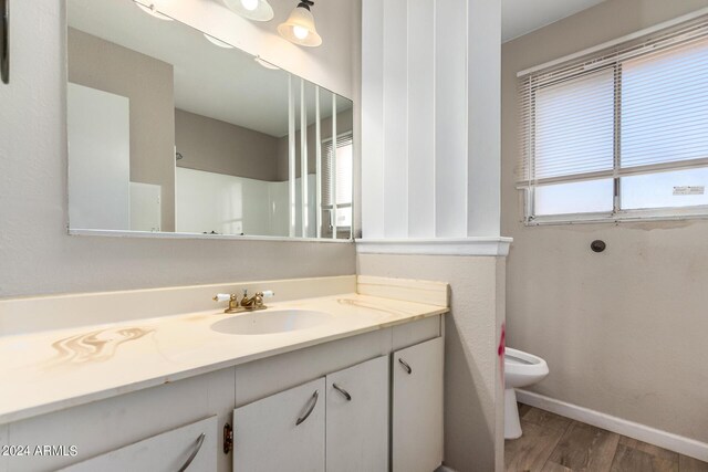 bathroom featuring hardwood / wood-style floors, vanity, toilet, and walk in shower