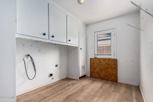 clothes washing area with cabinets, light wood-type flooring, hookup for a gas dryer, and electric dryer hookup