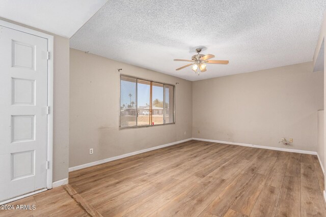 empty room featuring a textured ceiling, light hardwood / wood-style floors, and ceiling fan