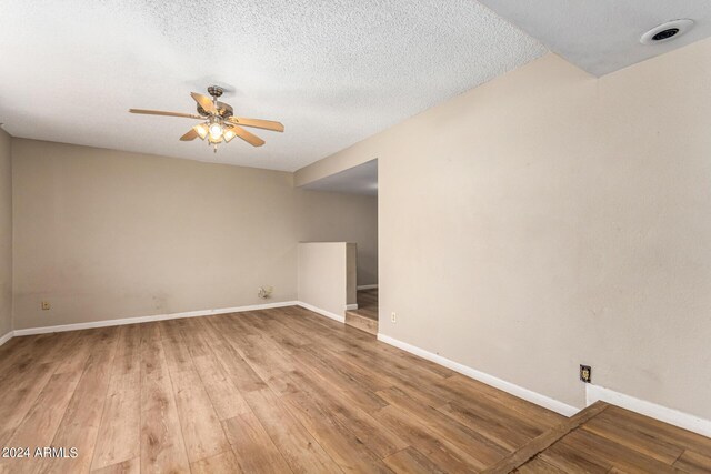 unfurnished room featuring a textured ceiling, light wood-type flooring, and ceiling fan