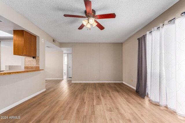 unfurnished living room with ceiling fan, a textured ceiling, and light hardwood / wood-style flooring