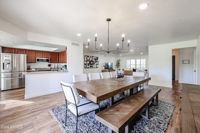 dining room with sink, a notable chandelier, and light wood-type flooring