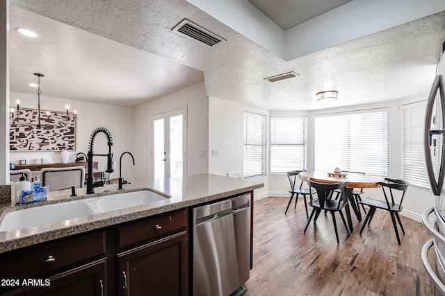 kitchen featuring light stone countertops, sink, wood-type flooring, decorative light fixtures, and dishwasher