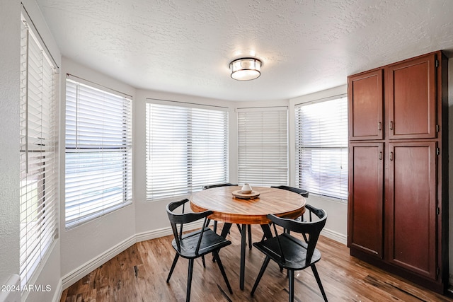 dining space featuring a textured ceiling, light wood-type flooring, and plenty of natural light