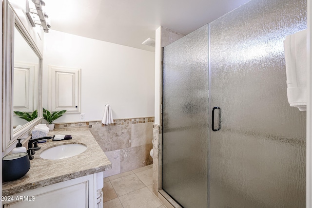 bathroom featuring tile patterned floors, a shower with door, and vanity