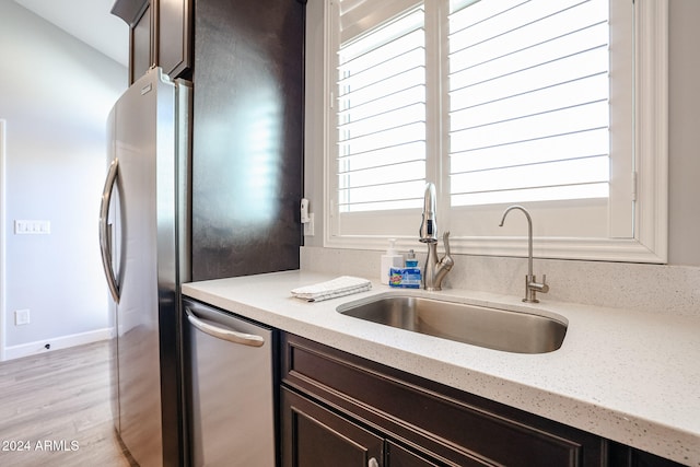 kitchen featuring light wood-type flooring, dark brown cabinetry, stainless steel appliances, and sink