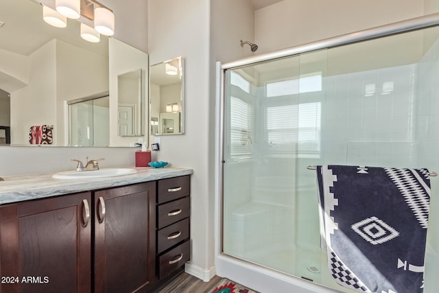 bathroom with hardwood / wood-style floors, vanity, and a shower with door