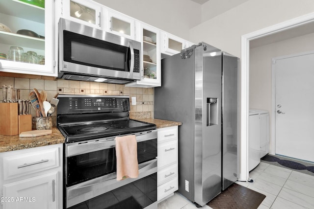 kitchen with decorative backsplash, stainless steel appliances, washer and dryer, stone countertops, and white cabinets