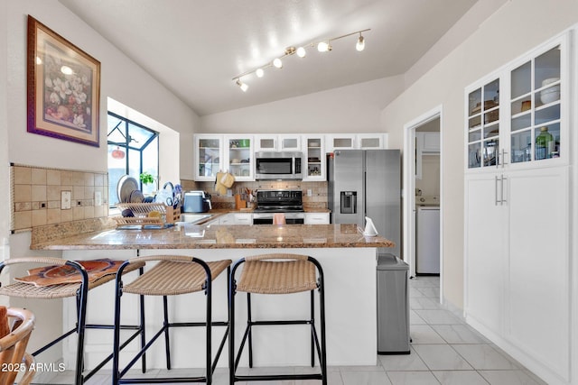 kitchen with tasteful backsplash, kitchen peninsula, stainless steel appliances, and lofted ceiling