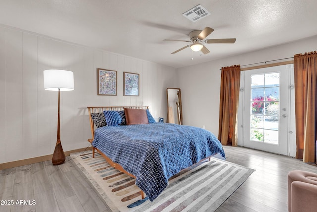 bedroom with ceiling fan, light hardwood / wood-style flooring, and a textured ceiling