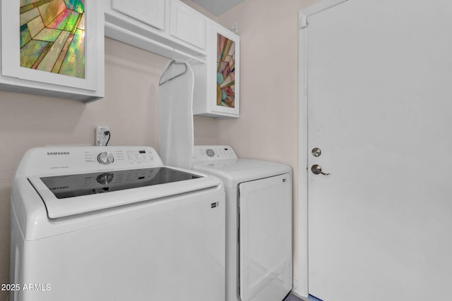 clothes washing area featuring washer and dryer and cabinets