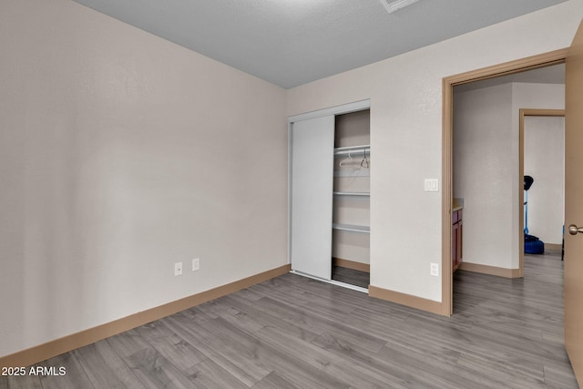 unfurnished bedroom with light wood-type flooring and a closet