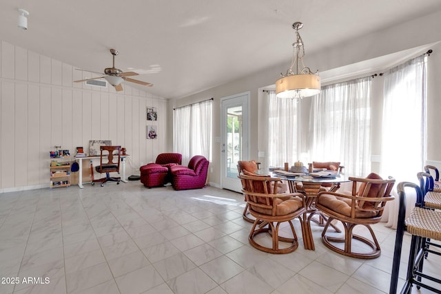 dining room with ceiling fan, wood walls, and lofted ceiling