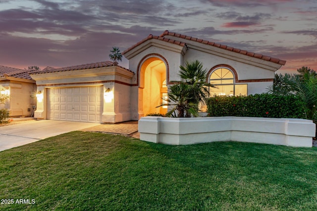 mediterranean / spanish house with a garage, a tile roof, concrete driveway, and a lawn