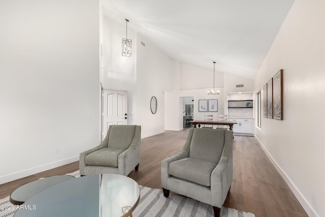 living room with a chandelier, high vaulted ceiling, wood finished floors, and baseboards