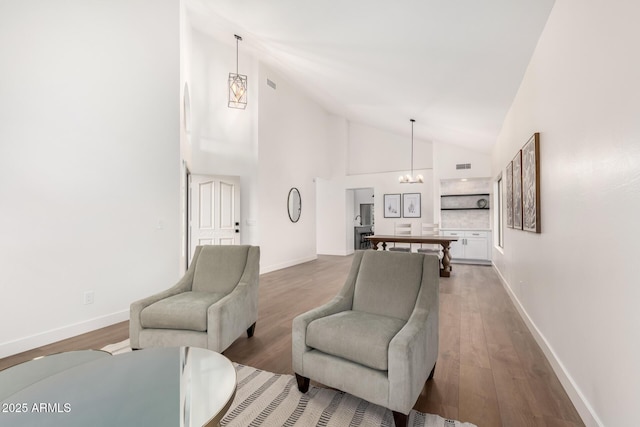 living room with a chandelier, wood finished floors, high vaulted ceiling, and baseboards