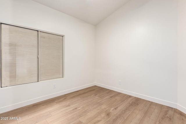 unfurnished room with light wood-type flooring, baseboards, and lofted ceiling