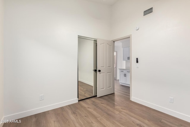 unfurnished room with baseboards, light wood-style floors, and a high ceiling