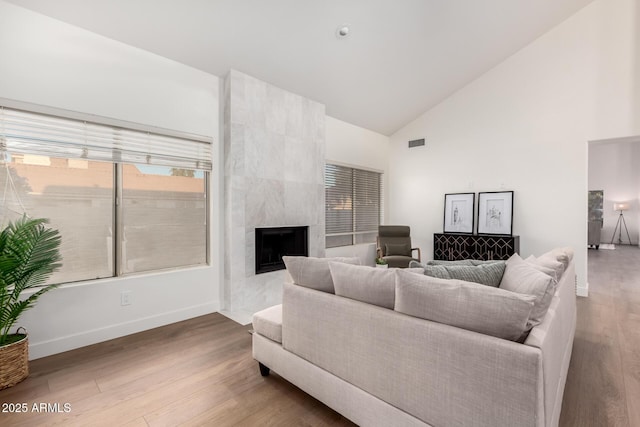 living area featuring high vaulted ceiling, wood finished floors, baseboards, and a fireplace