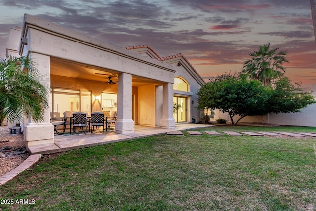 back of house with a ceiling fan, a yard, a patio area, and stucco siding