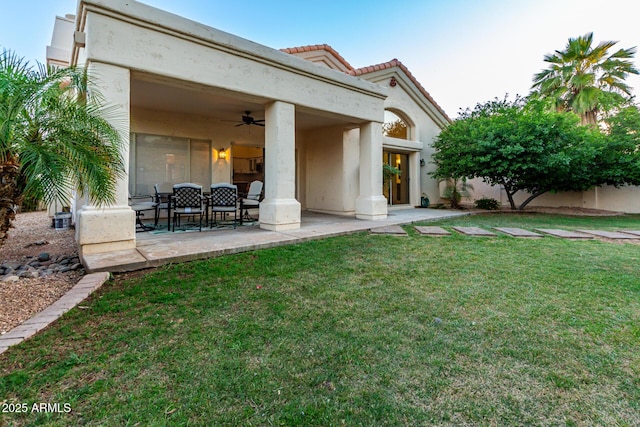 back of property featuring a ceiling fan, a yard, a patio, and stucco siding