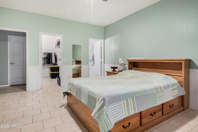 tiled bedroom featuring ensuite bathroom, a walk in closet, and a closet