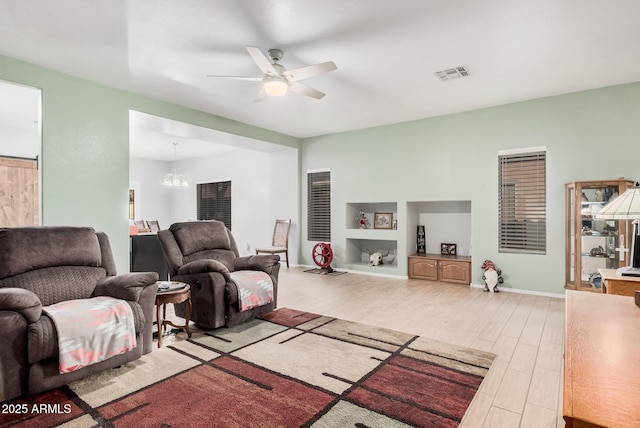 living room with ceiling fan with notable chandelier and light hardwood / wood-style floors