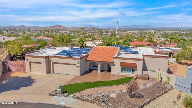 view of front facade with a mountain view, a garage, and solar panels