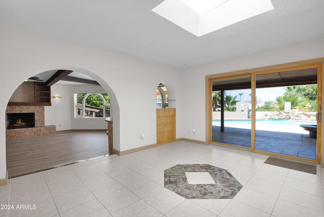 empty room with light wood-type flooring and beam ceiling