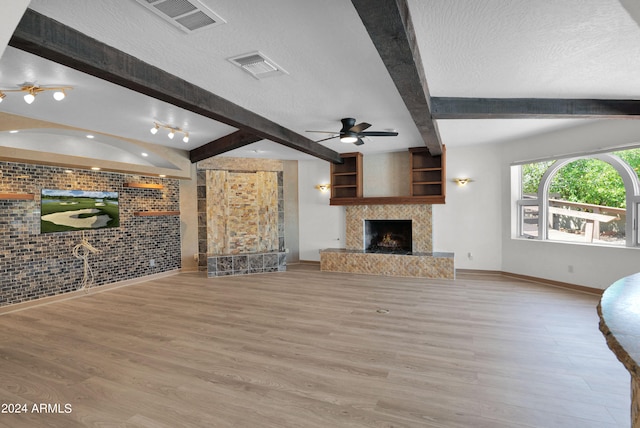 unfurnished living room featuring beamed ceiling, a high end fireplace, and a textured ceiling