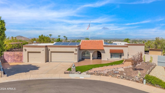 view of front of home featuring a mountain view, solar panels, and a garage