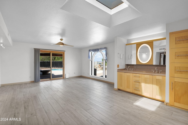 interior space with a skylight, wood finished floors, baseboards, and a sink