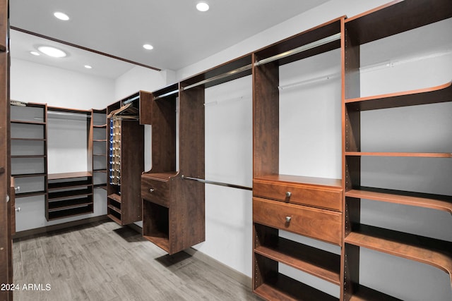 walk in closet with light hardwood / wood-style flooring