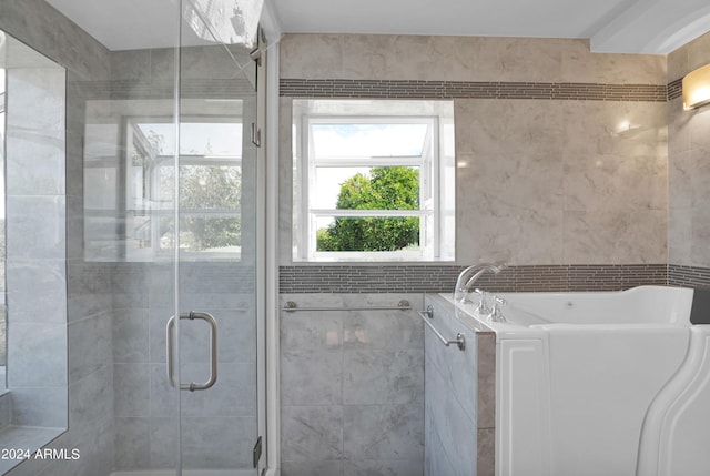 bathroom with tile walls, a stall shower, and a bath