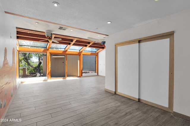 empty room featuring a textured ceiling, wood-type flooring, and ceiling fan