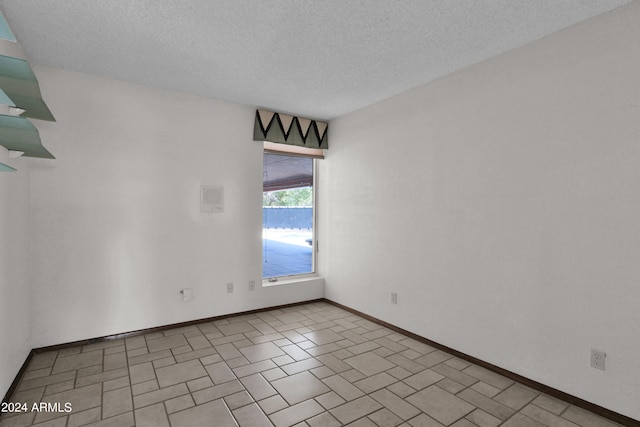 empty room featuring a textured ceiling and baseboards