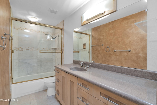 full bathroom featuring tile patterned floors, vanity, toilet, and combined bath / shower with glass door