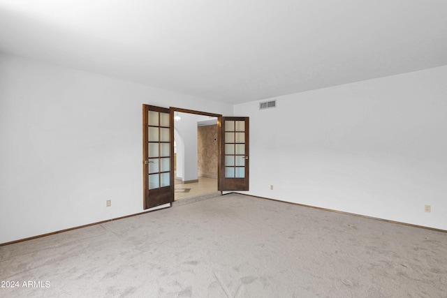 carpeted spare room featuring french doors, baseboards, and visible vents