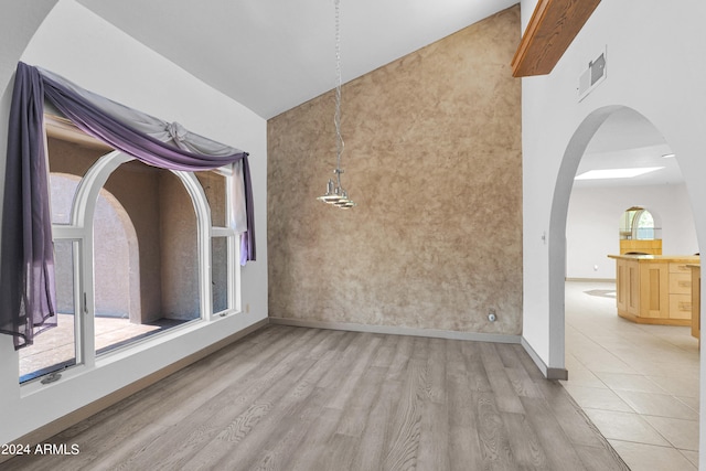 unfurnished room featuring high vaulted ceiling, plenty of natural light, and light hardwood / wood-style flooring