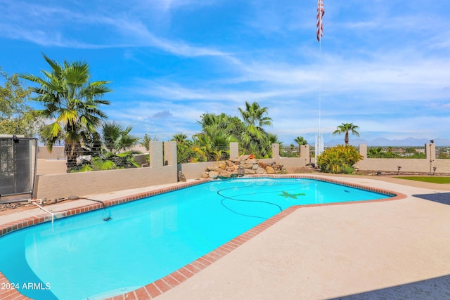 pool featuring a patio, fence, and a mountain view