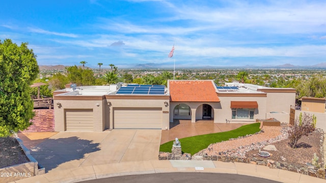 view of front of house featuring solar panels, a garage, and a mountain view