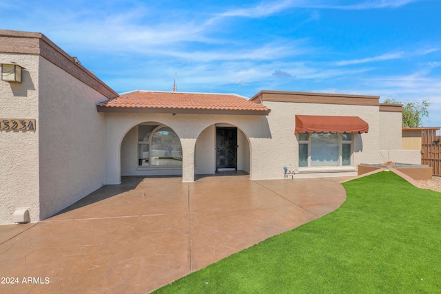 back of house featuring a patio area, stucco siding, a tiled roof, and a lawn