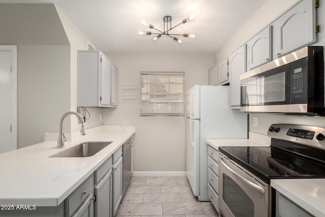 kitchen featuring marble finish floor, gray cabinetry, a sink, appliances with stainless steel finishes, and an inviting chandelier