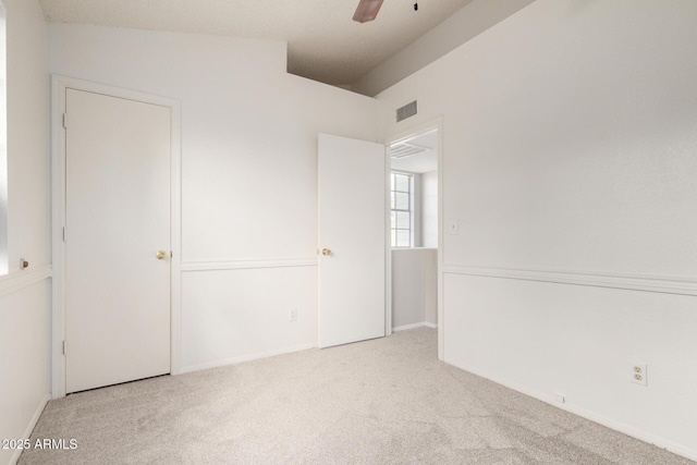 carpeted spare room featuring visible vents, ceiling fan, and vaulted ceiling