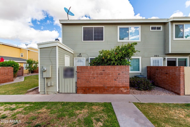 rear view of property featuring a gate, a yard, and fence