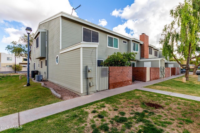 view of property exterior featuring central air condition unit, a residential view, a lawn, and fence