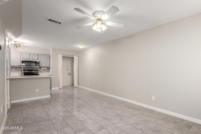 interior space featuring baseboards, visible vents, stainless steel appliances, and a ceiling fan