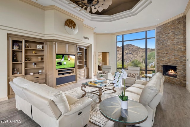 living room featuring hardwood / wood-style floors, a fireplace, crown molding, and a towering ceiling