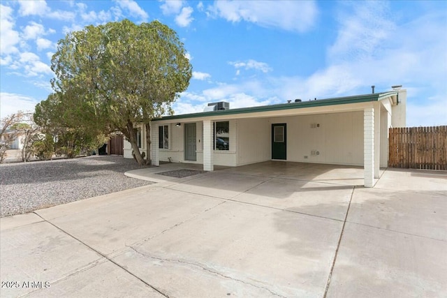 ranch-style home with a carport, concrete driveway, central AC, and fence