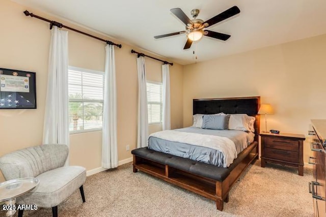 bedroom featuring light colored carpet, baseboards, and a ceiling fan